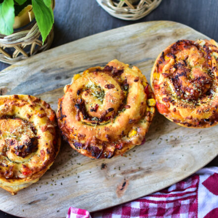 XL Airfryer Pizzaschnecken im BBQ-Style frisch aus der Heißluftfritteuse auf einem Brettchen serviert.
