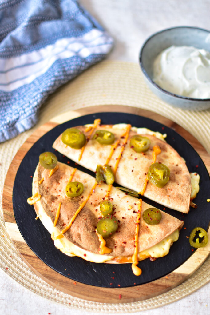 Nahaufnahme einer angeschnittenen Quesadilla aus der Heißluftfritteuse, bei der geschmolzener Käse aus der knusprigen Tortilla austritt.