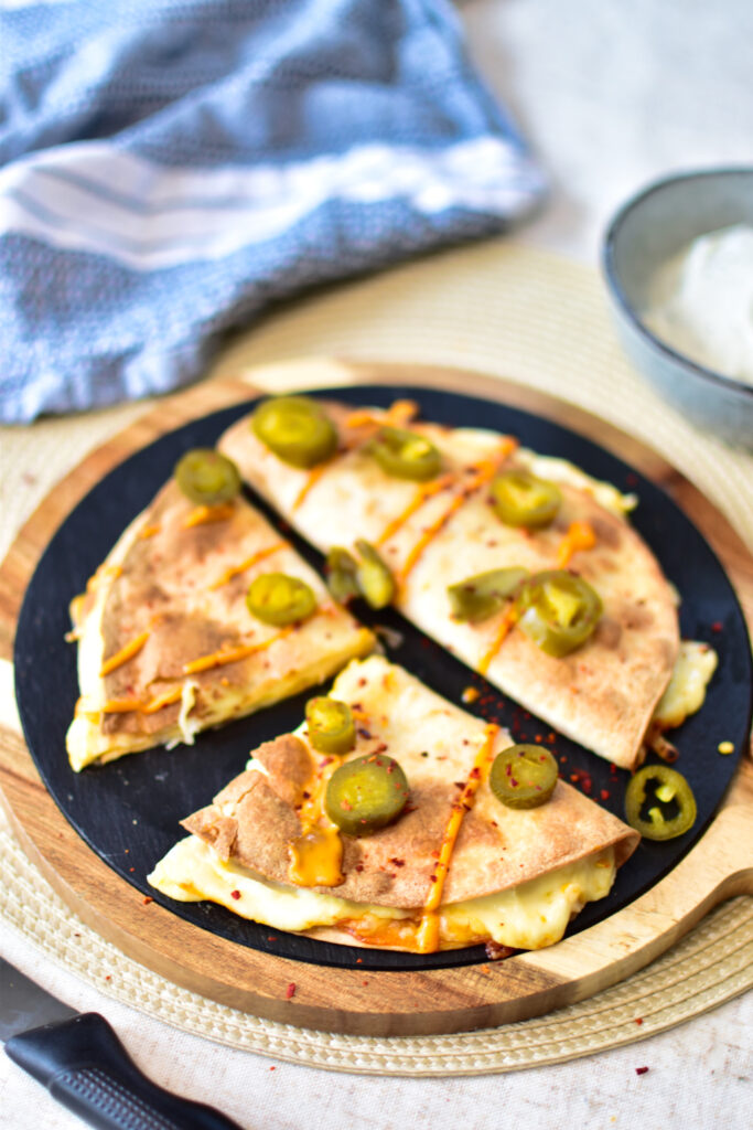 Goldbraun gebackene Quesadillas aus dem Airfryer auf einem rustikalen Holzteller, serviert mit einem Klecks cremiger Sriracha-Mayo.