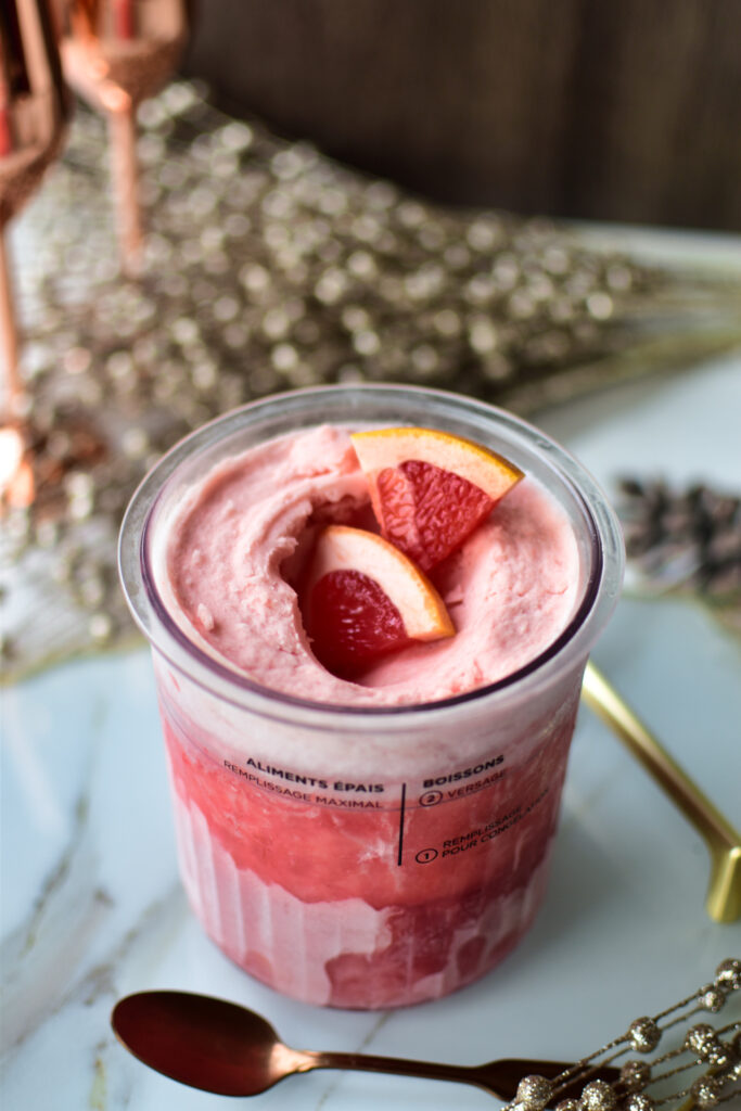 Cremiges Grapefruit Sorbet im Ninja Creami Behälter auf einem hellen Marmor-Tablett.