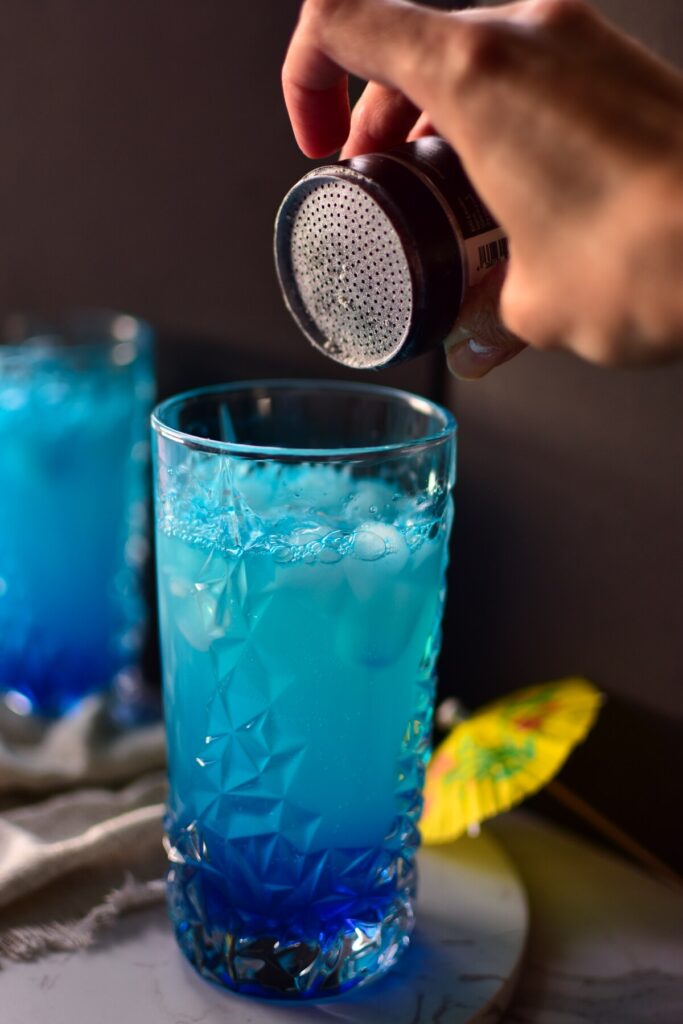 Alkoholfreier Cocktail wird mit Glitzer bestreut. Mit der Blauen Farbe vom Sirup bekommt er einen wundervollen Schimmer Effekt.