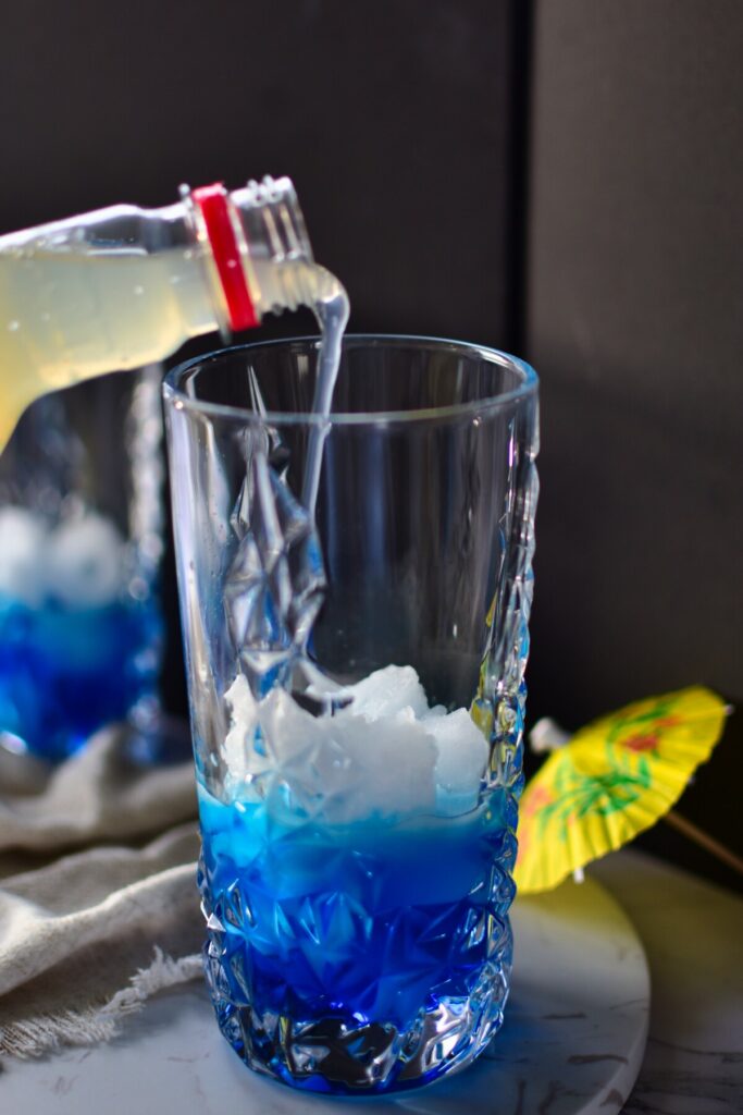 Blauer alkoholfreier Cocktail wird mit Limettenlimonade aufgefüllt.
