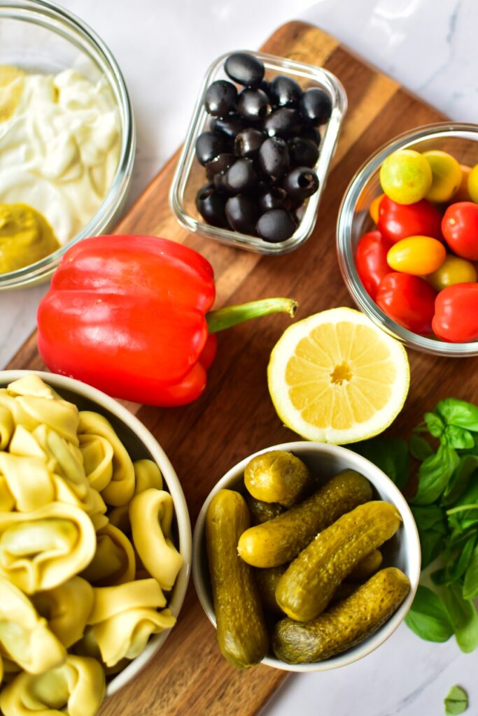 Alle Zutaten für Tortellini Salat auf einen Blick: Paprika, Oliven, Gurken, Tomaten und gekochte Tortellini. 