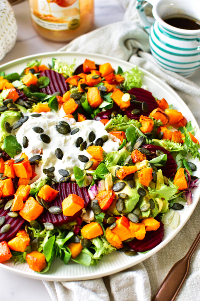 Kürbissalat mit Burrata auf einer großen Servierplatte angerichtet. Mit roter Beete und Balsamico-Senf Dressing.