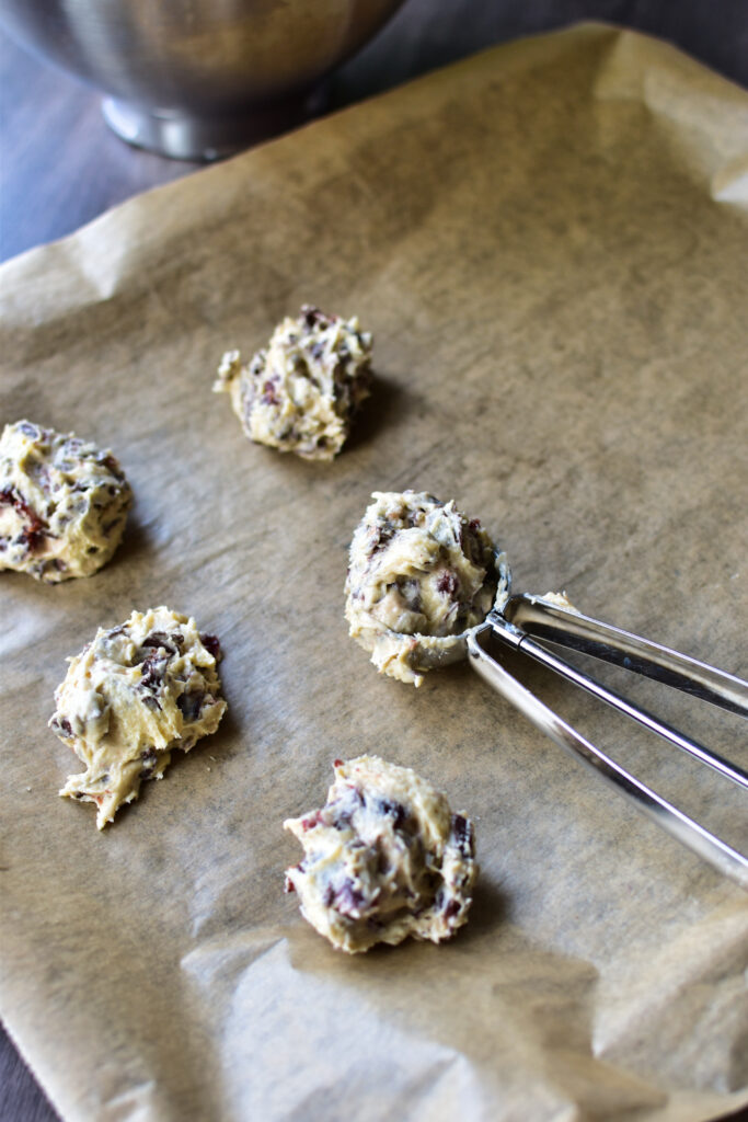 Amerikanische Cookies werden mit einem Portionierer auf dem Backblech verteilt.