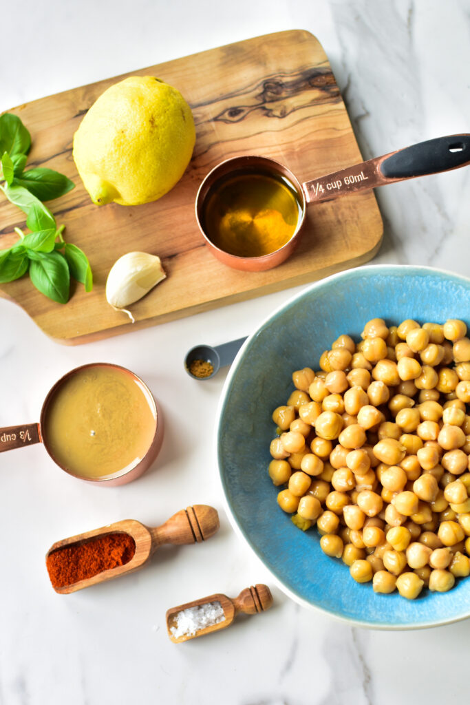 Zutaten für ein einfaches Hummus Rezept: Kichererbsen, Zitrone, Tahini, gerösteter Knoblauch und Olivenöl.