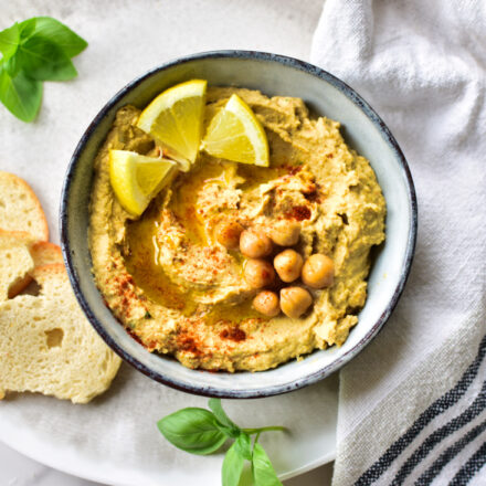 Cremiger Hummus mit frischem Zitronenabrieb, angerichtet in einer Schüssel mit Olivenöl und geräuchertem Paprikapulver.