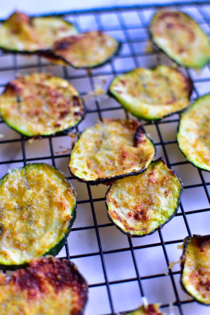 Zucchini-Chips goldbraun und knusprig, frisch aus der Heißluftfritteuse, auf einem Abkühlgitter.