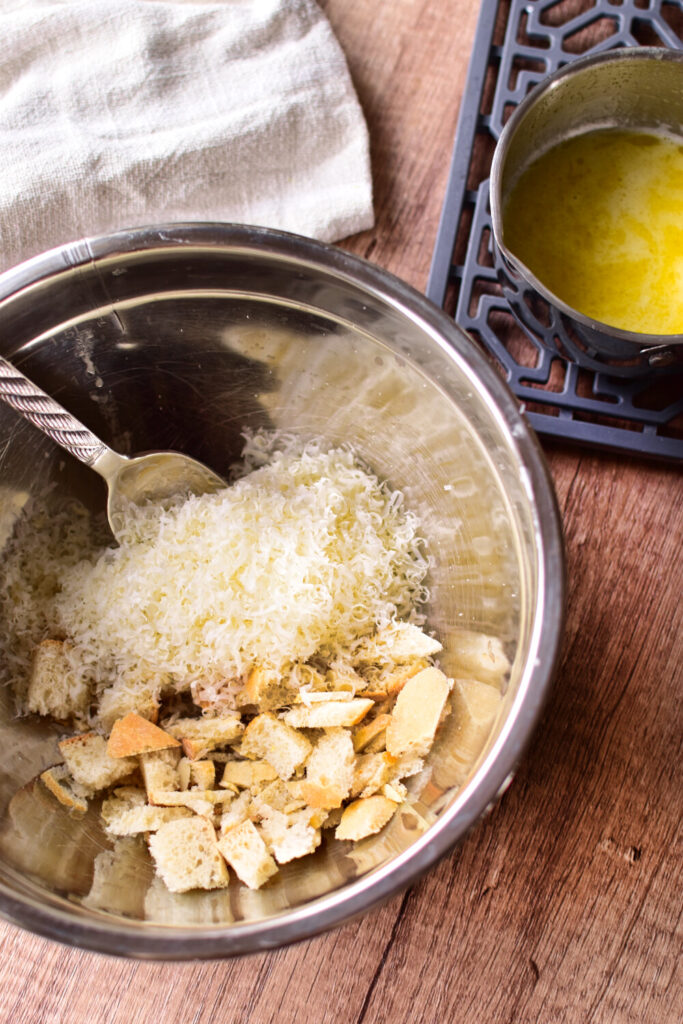 Das Topping wird hergestellt: Parmesankäse und Semmelbrösel in einer Rührschüssel, daneben die geschmolzene Butter.