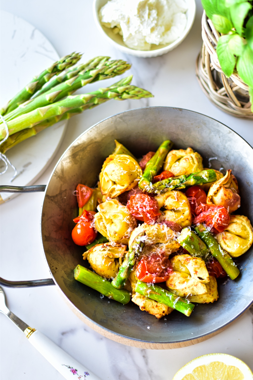 Angerichtete Tortellini mit Spargel, Tomaten, Parmesan, Ricotta und Zitronensaft.