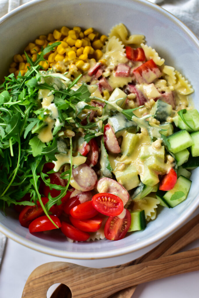 Frische Zutaten für Nudelsalat: Paprika, Tomaten, Rucola, Hummus