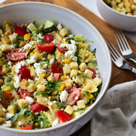 Nudelsalat in einer Schüssel mit Kräutertopping und Sonnenblumenkernen