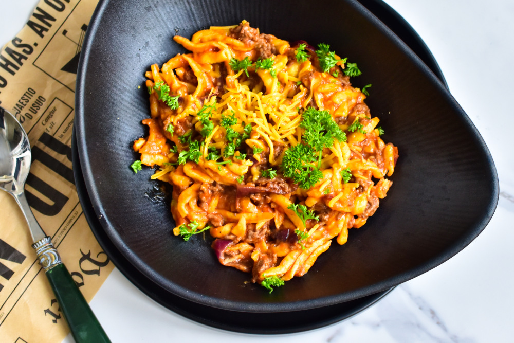 Frisch zubereitete Cheeseburger Spätzle in der Pfanne mit geschmolzenem Cheddar
