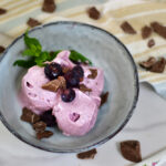 Blaubeer Frozen Joghurt im Ninja Creami Deluxe mit frischen Blaubeeren und gehackter Schokolade serviert in einem Becher