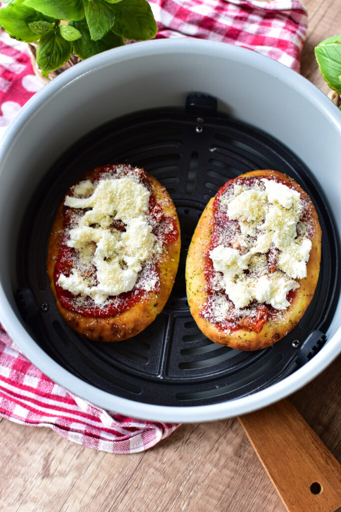 Vorbereitung eines einfachen Airfryer Snacks: Naanbrot mit Tomatensauce, Mozzarella und Salami belegen.