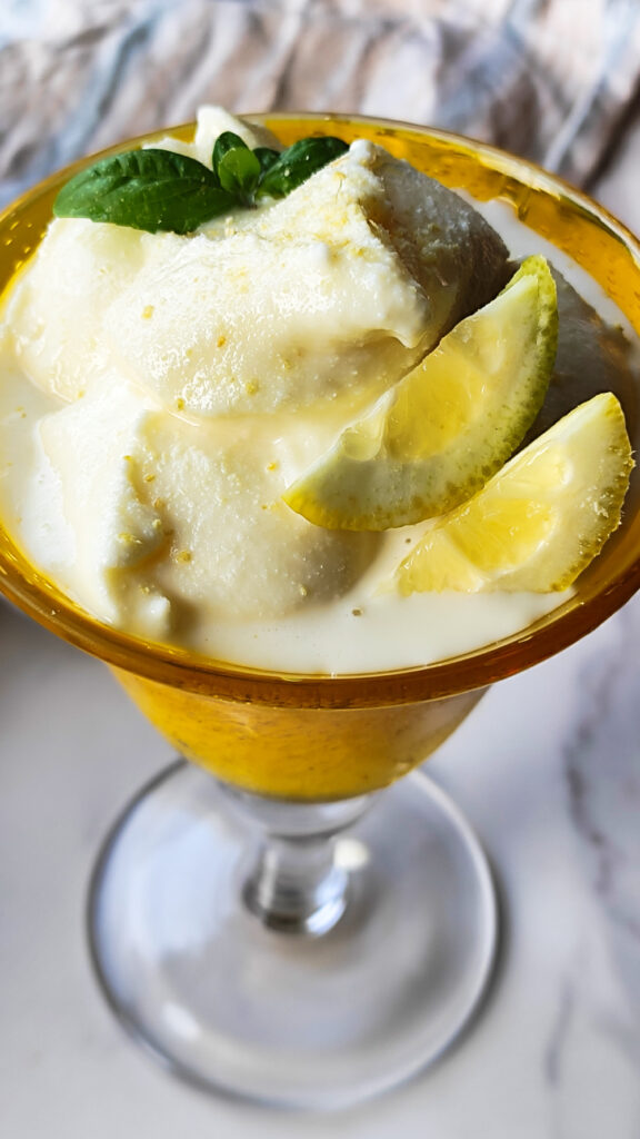 Cremiges weiches Eis mit Limoncello in einem gelben Becker serviert.
