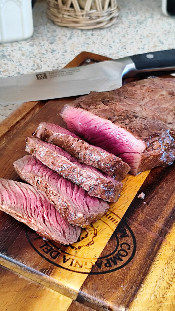 Saftiges Steak aus der Heißluftfritteuse angeschnitten auf einem Brett serviert.