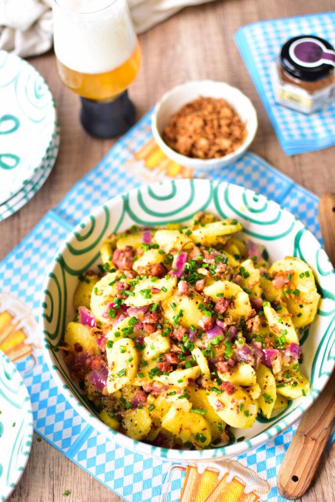 Deftiger Kartoffelsalat mit Bier-Dressing, knusprigem Speck und Zwiebeln.