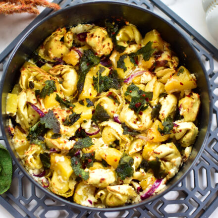 Rezept für herbstlichen Kürbis-Feta-Tortellini-Topf mit frischem Salbei im Topf serviert.