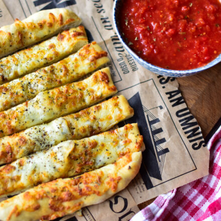 Pizzastangen serviert mit Tomatendip und Knoblauchbutter in kleinen Schalen