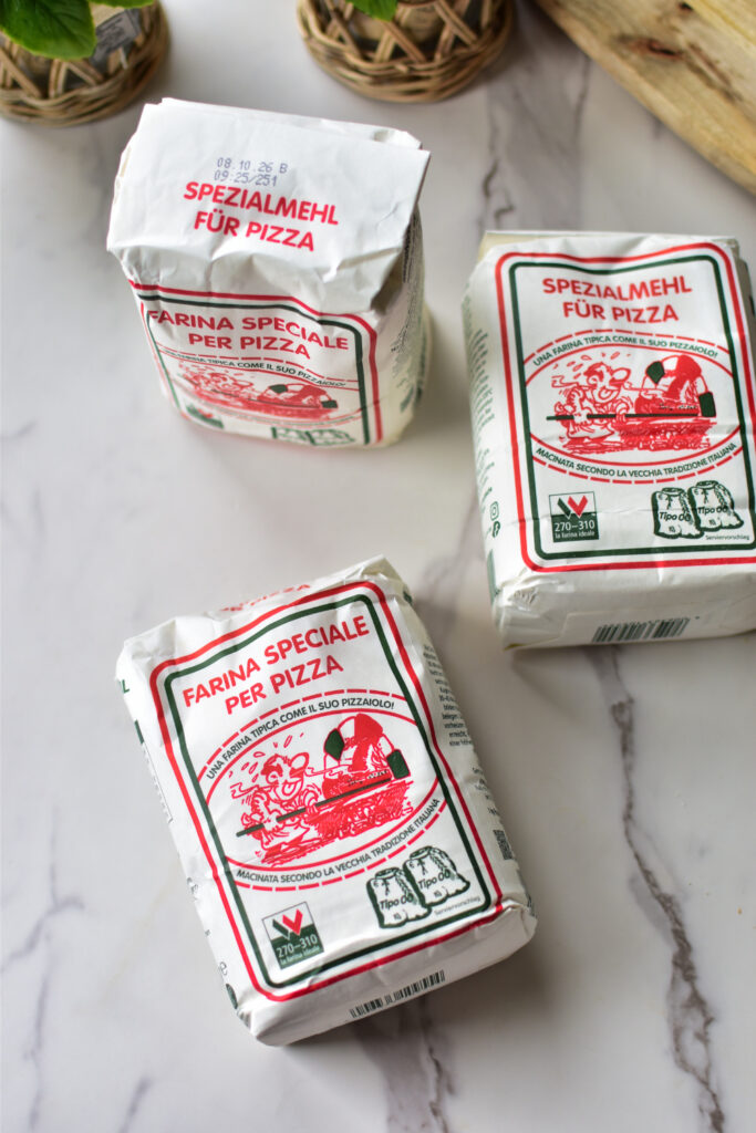 Das beste Mehl für Pizza. 3 Mehlpackungen auf einer Küchenarbeitsplatte.