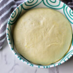 Einfacher Pizzateig in einer grünen Schüssel - bereit zur Pizza verarbeitet zu werden.