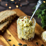 Cremige Knoblauchbutter mit Kürbiskernen und Chili – festlich angerichtet auf Holzbrett