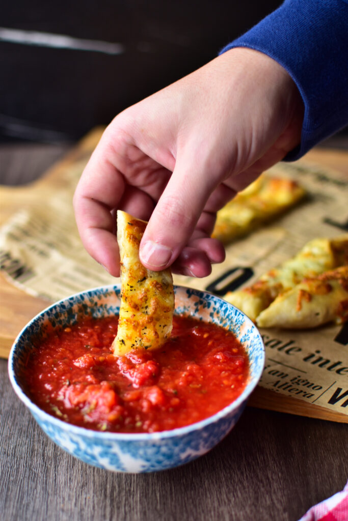 Die Pizzastangen aus der Heißluftfritteuse werden in Tomatensauce gedippt.