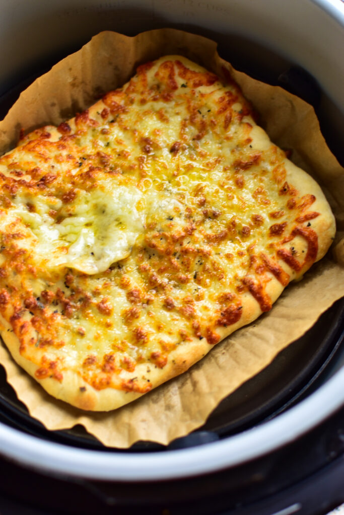 Detailaufnahme goldbrauner Mozzarella auf frisch gebackenen Pizzastangen