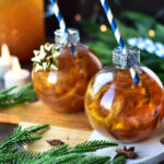 Selbstgemachter goldener Weihnachtspunsch mit Apfel, Zimt und Anis, liebevoll angerichtet in Seaside No.64 Baumkugel-Gläsern mit Strohhalm und goldenen Akzenten.