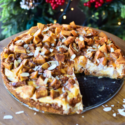 Bratapfel-Cheesecake mit Karamellsoße auf einem Holz Kuchenständer serveriert.
