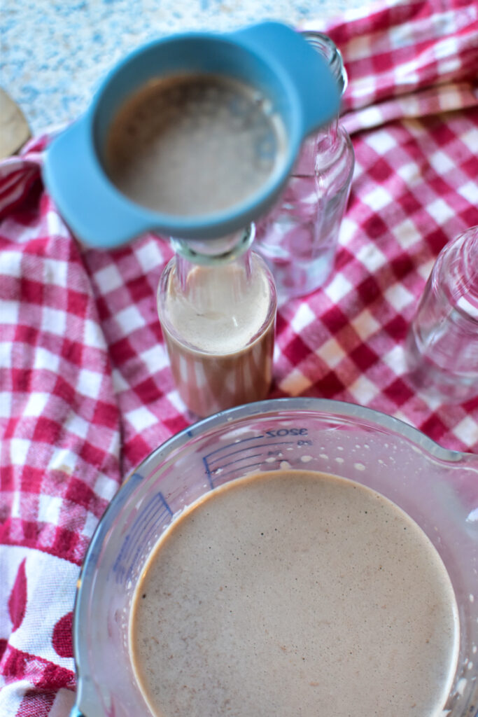 Hausgemachter Lebkuchen Likör in edlen Flaschen gefüllt mit einem blauen Trichter
