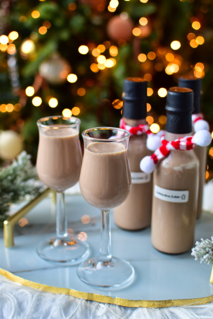 Weihnachtlicher Lebkuchen Likör mit Likör 43, Sahne und Lebkuchengewürz in kleinen Likör-Gläschen vor einem Weihnachtsbaum – aromatisch und cremig.