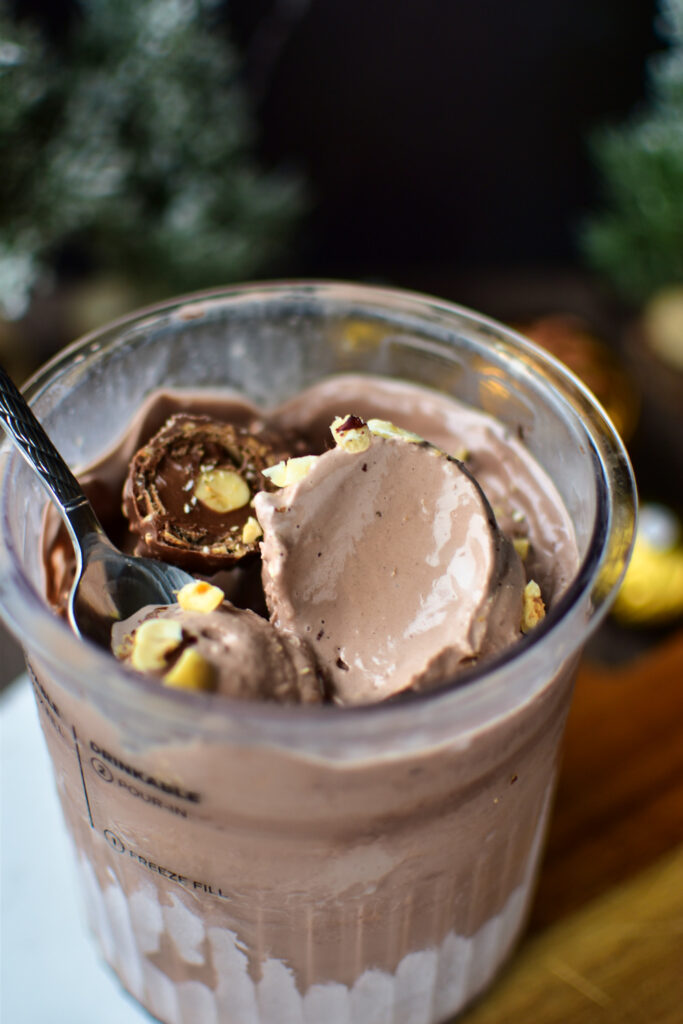 Cremiges Rocher Eis aus dem Ninja Creami Deluxe mit Schokolade und Haselnuss-Crunch wird mit einem Löffel gegessen.