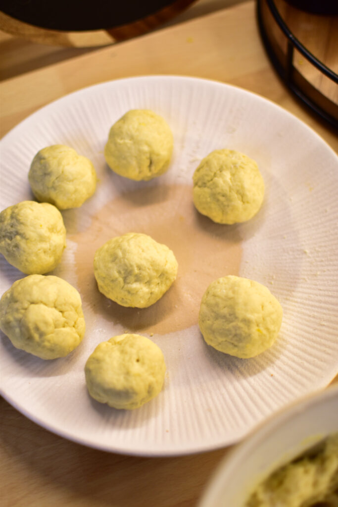 Schritt für Schritt Zubereitung der Quarkbällchen auf einem Teller vorm Backen.