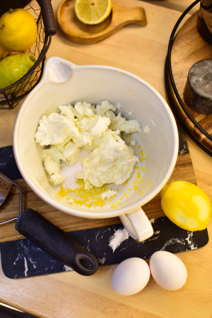 Zutaten für das einfache Rezept mit Zitronen, Eiern und Quark auf einem Brett.