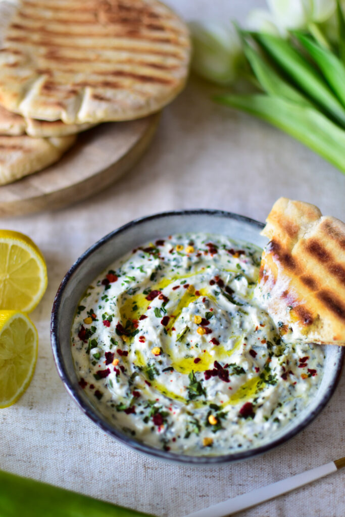 Bärlauch Dip mit Feta und Olivenöl Topping mit knusprigem Pita-brot serviert.