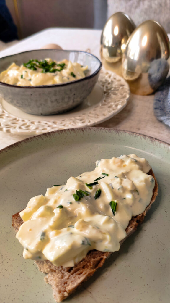 Cremiger Eiersalat auf einem rustikalen Brot serviert.