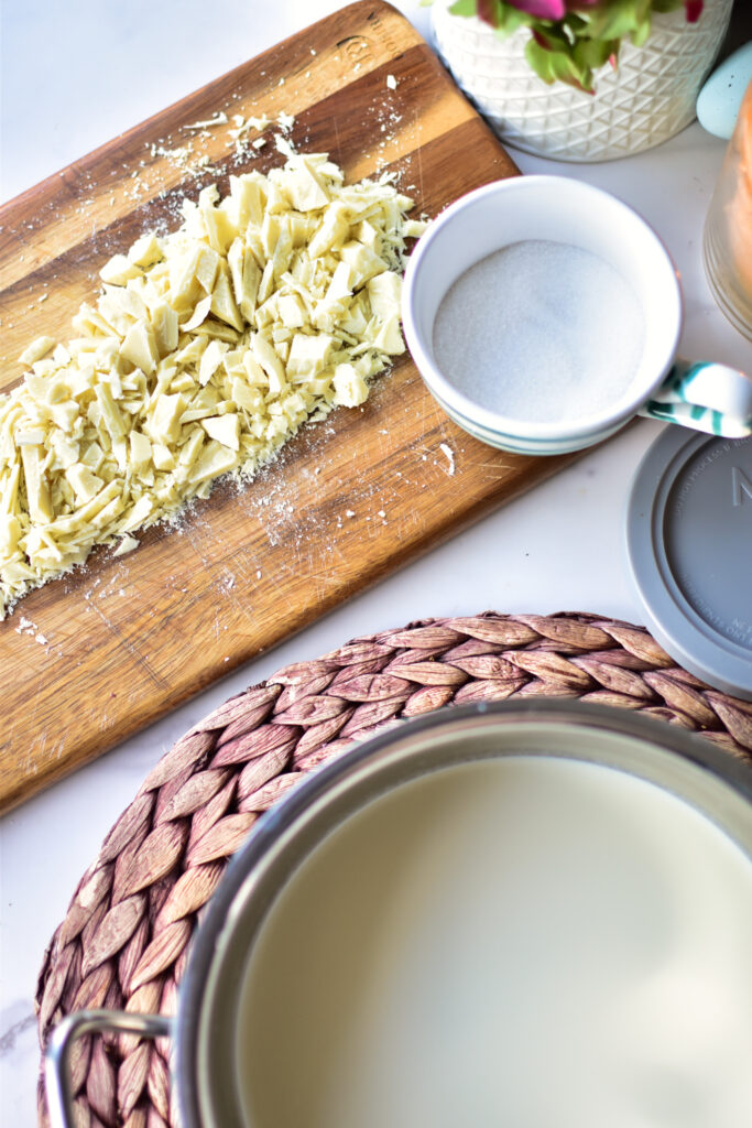 Vorbereitung der Basis für Ninja CREAMi Deluxe Weiße Schokolade im Topf mit gehackter Schokolade auf einem Tablett.