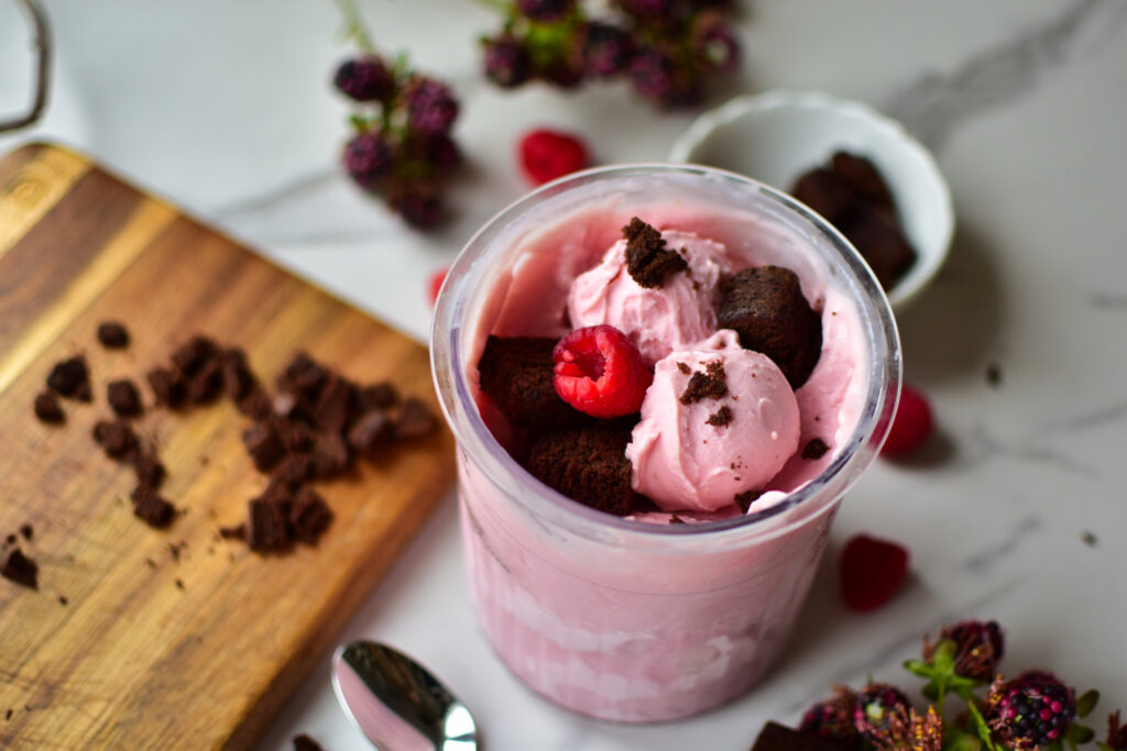 Cremiges rosa Himbeereis aus der Ninja Creami im Deluxe Becher serviert.