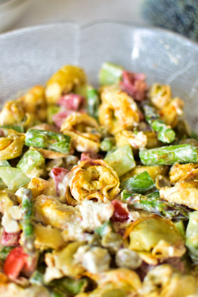 Nahaufnahme vom fertigen Crispy Tortellinisalat mit grünem Spargel, getoppt mit cremigem, zerbröseltem Feta-Käse.