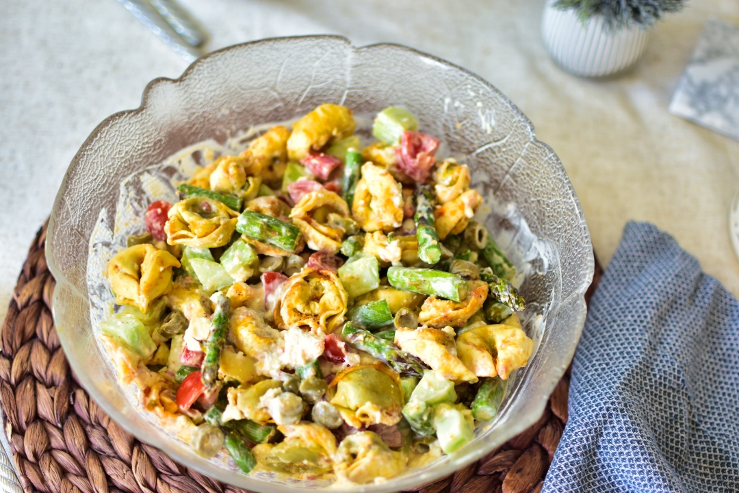 Lauwarmer Tortellinisalat mit knusprig panierten Tortellini aus dem Airfryer und grünem Spargel in einer stylischen Schüssel, fertig serviert für die Grillparty.