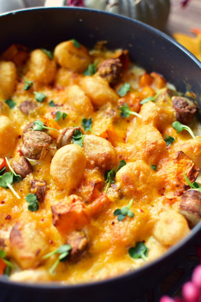 Nahaufnahme des cremigen Gnocchi-Auflaufs aus dem Airfryer mit Hokkaido, würziger Bratwurst und geschmolzenem Käse.