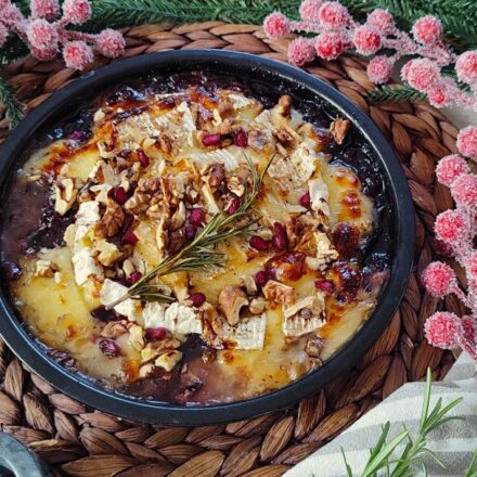 Camembert im Airfryer mit geschmolzenem Käse, Wildpreiselbeeren, Walnüssen und Rosmarin in einer kleinen Airfryer-Form serviert.