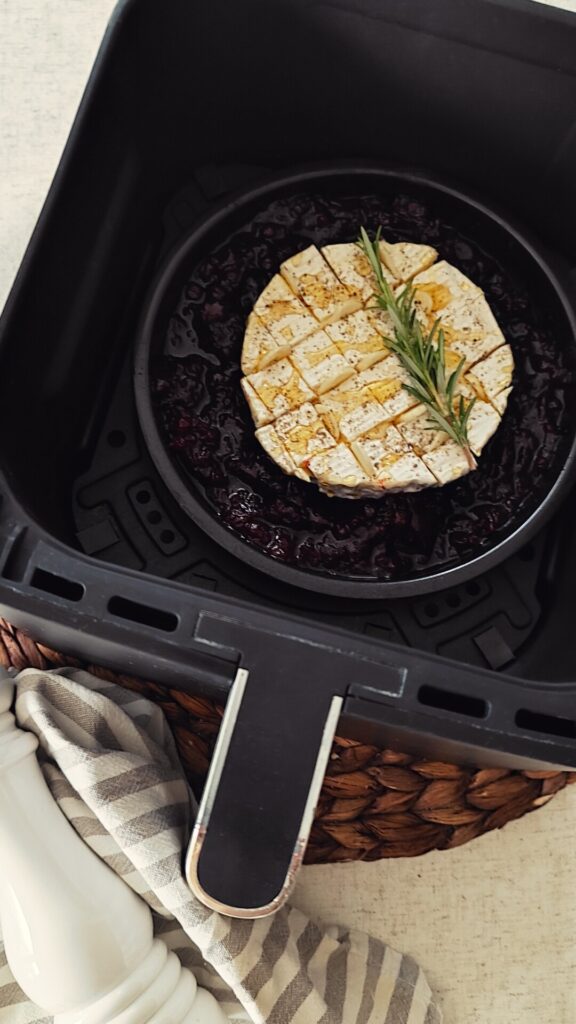 Camembert wird im Ninja Airfryer gebacken zusammen mit Cranberries in einer Auflaufform.